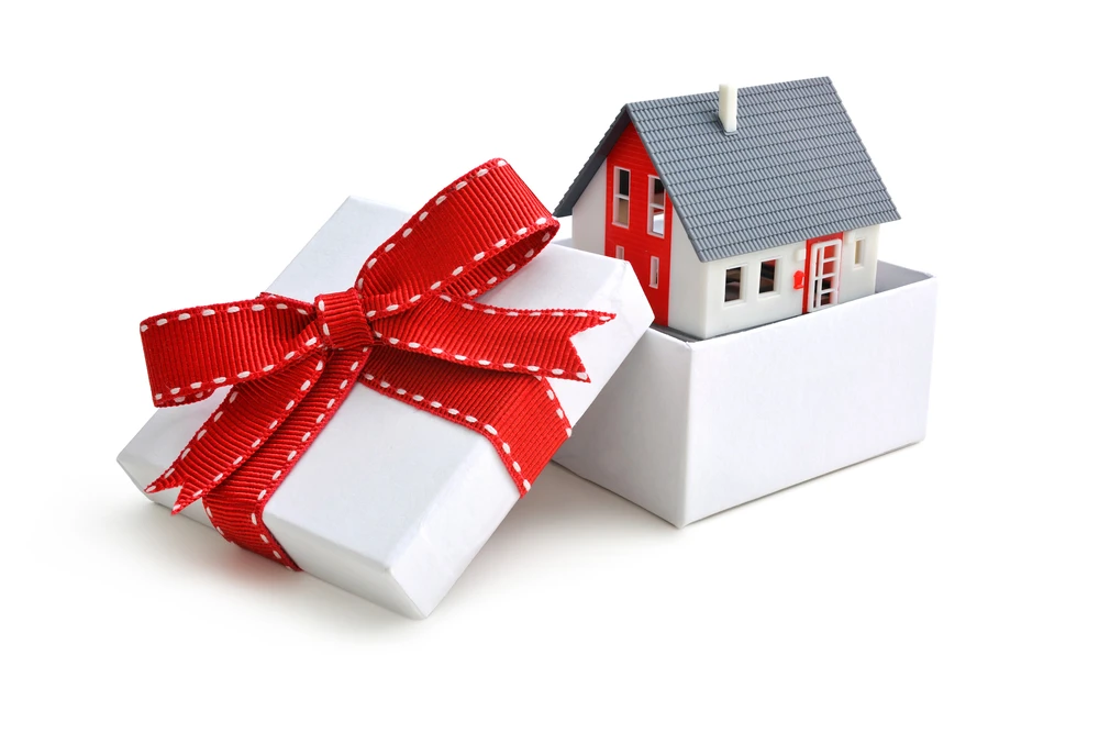 Model of a house in gift box with red ribbon